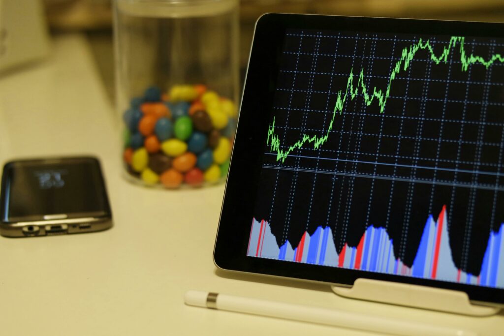 Gráfico financeiro mostrando crescimento em tela digital, com smartphone e caneta ao lado.