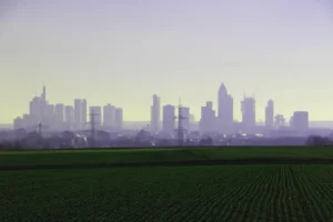Skyline urbano ao fundo e plantação em primeiro plano, representando os lastros imobiliário e agro da LCI e da LCA